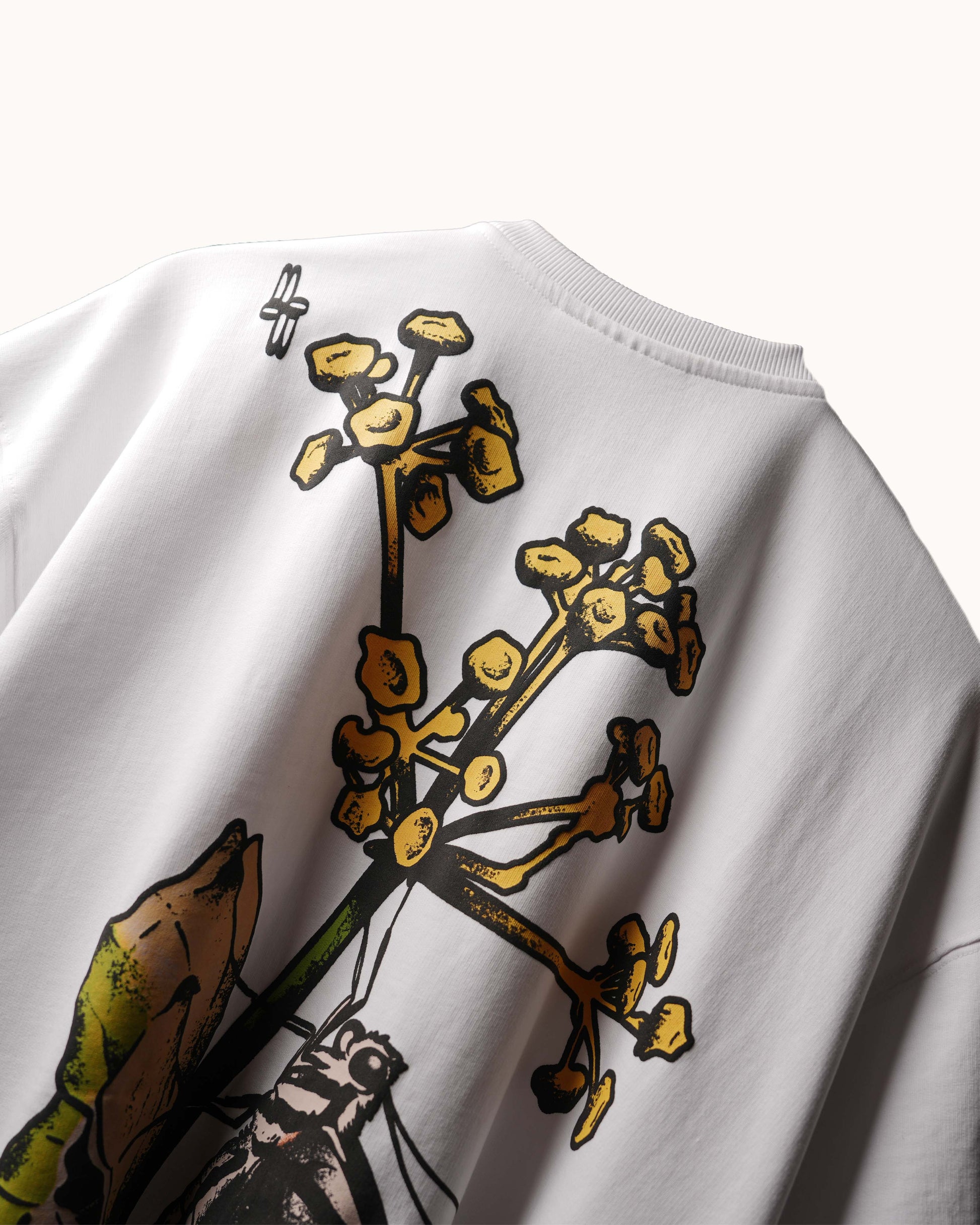 Close-up of a white crewneck sweatshirt featuring a graphic print of yellow flowers and green leaves on the front.
