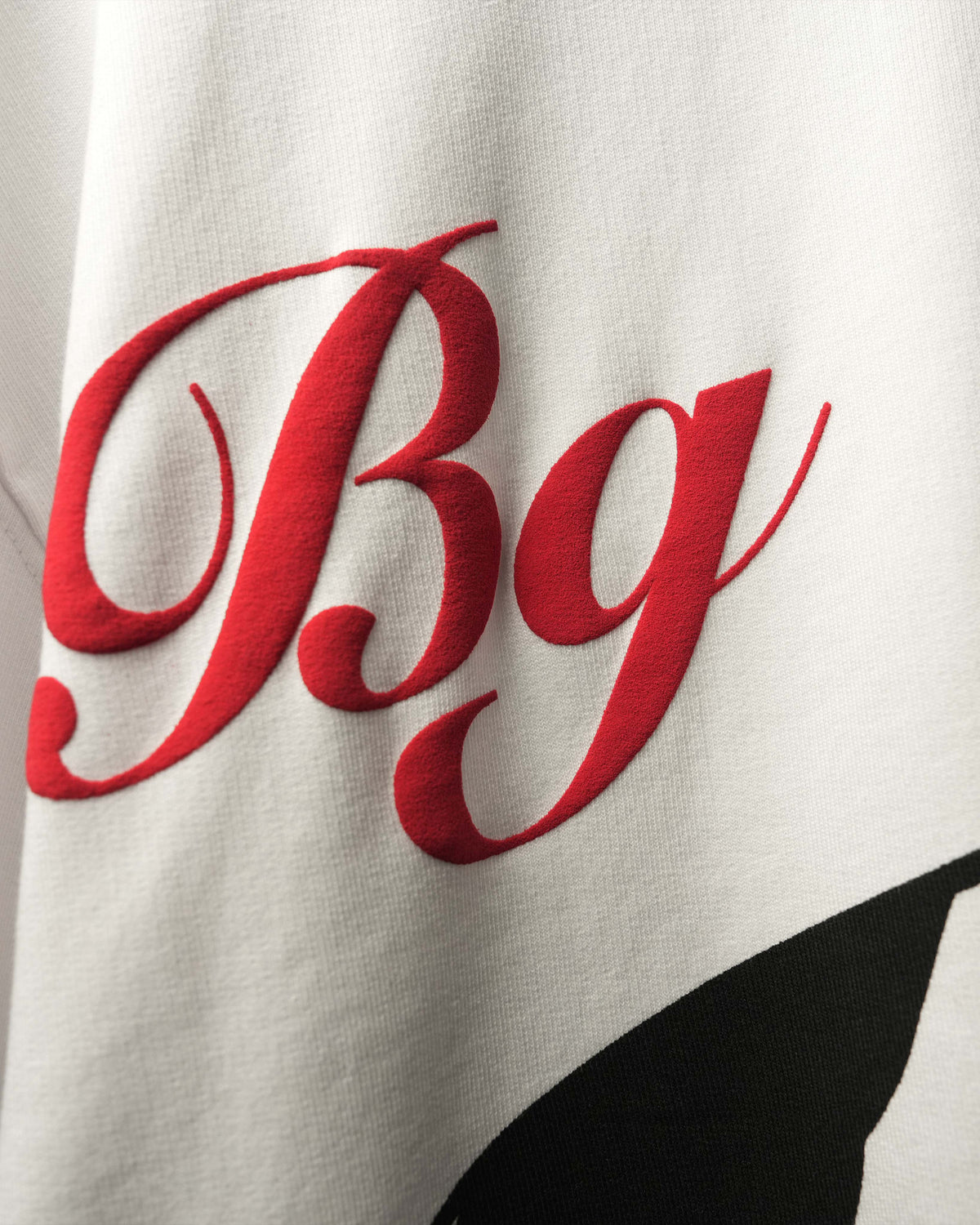 Close-up of a white fabric surface with large red BG script letters and a partial black graphic.